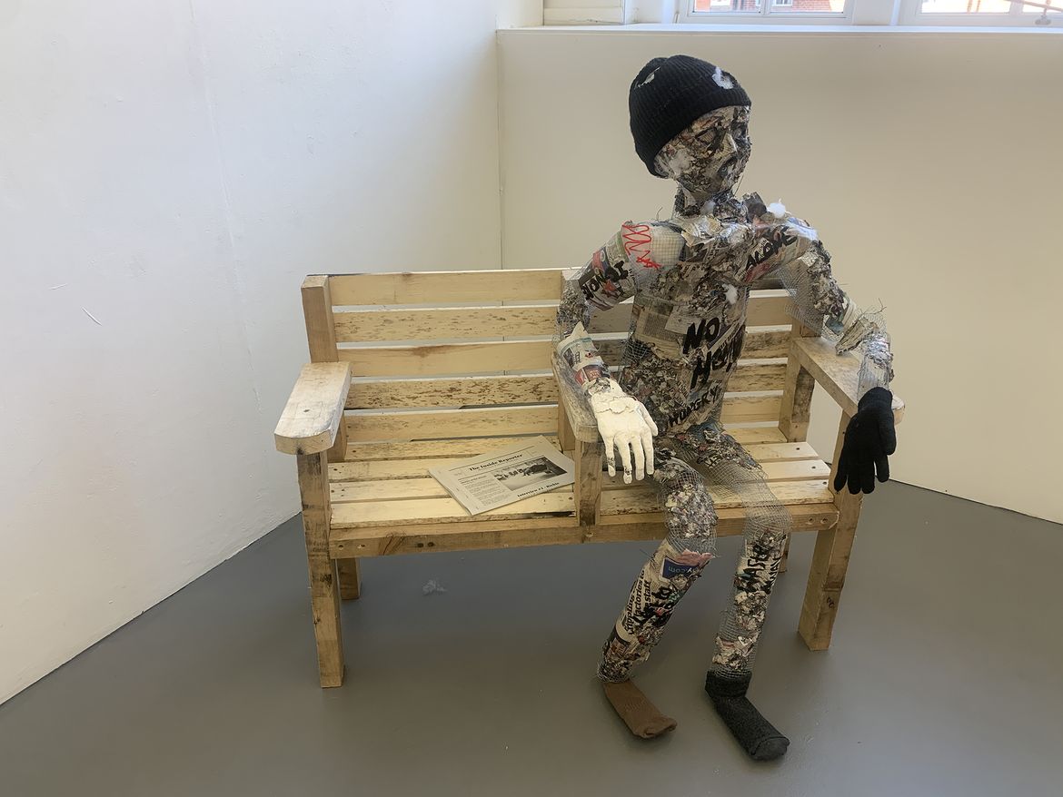 A fake skeleton covered in paper sitting on a bench