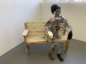 A fake skeleton covered in paper sitting on a bench