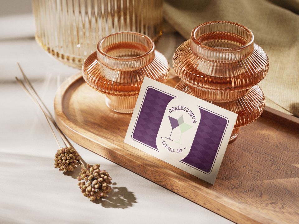 Photo of a purple business card with an image of cocktails on leaning against jars on a table