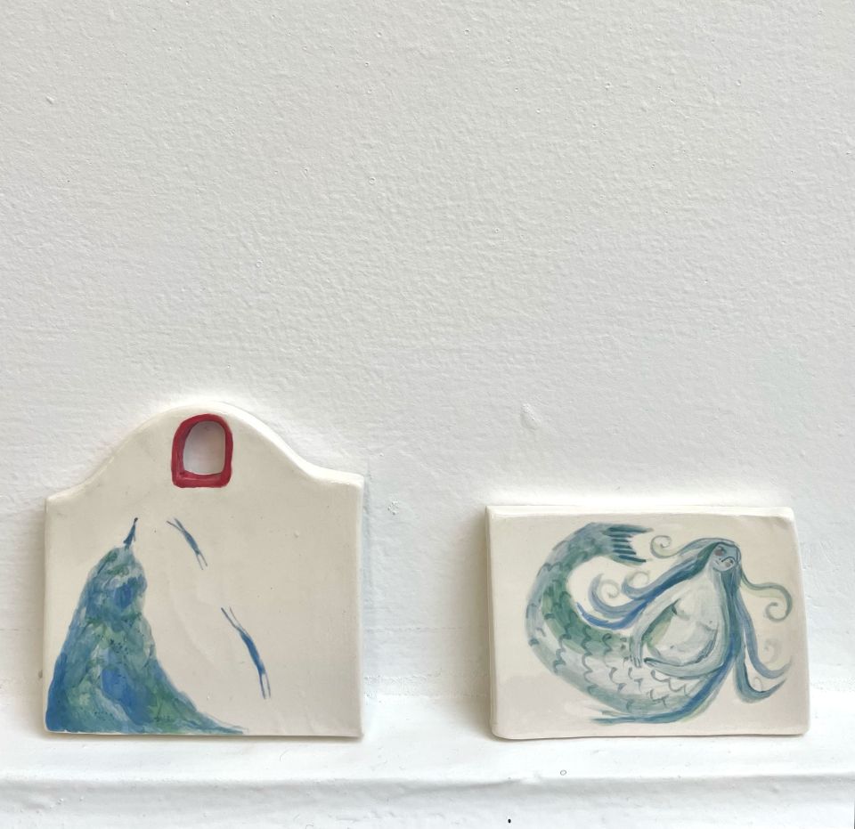 Two ceramic tiles with mermaid illustrations