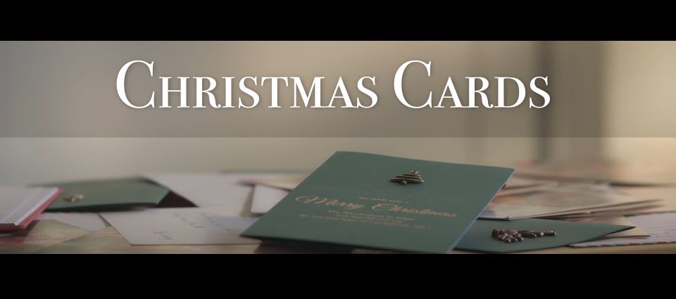 Film still showing green cards scattered on table with title "Christmas Cards" above
