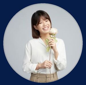 Amanda Lee in a white blouse holds a light pink rose against a gray background, framed by a circular blue border.