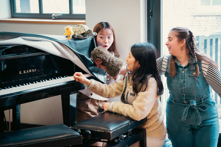 Two people with puppets and a piano