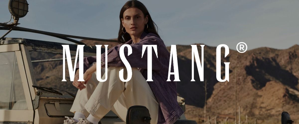 Eine Frau in einer violetten Jacke sitzt auf einem Fahrzeug, im Hintergrund sind Berge zu sehen. Das Logo der Marke Mustang überlagert das Bild.