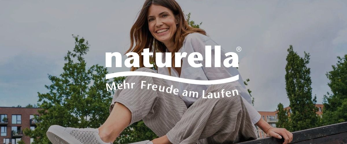 Eine lächelnde Frau in Freizeitkleidung sitzt im Freien vor dem Hintergrund von Bäumen. Das Logo der Marke naturella überlagert das Bild.