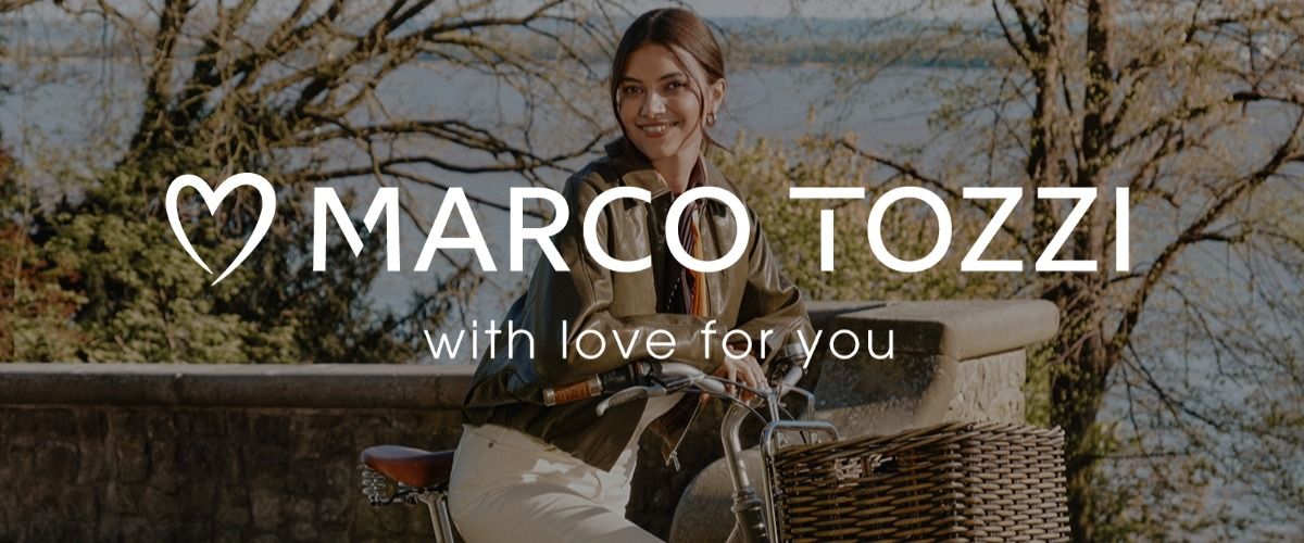 Eine Frau, die lächelnd auf einem Fahrrad mit Korb sitzt, draußen in einer Parklandschaft. Das Logo der Marke MARCO TOZZI überlagert das Bild.