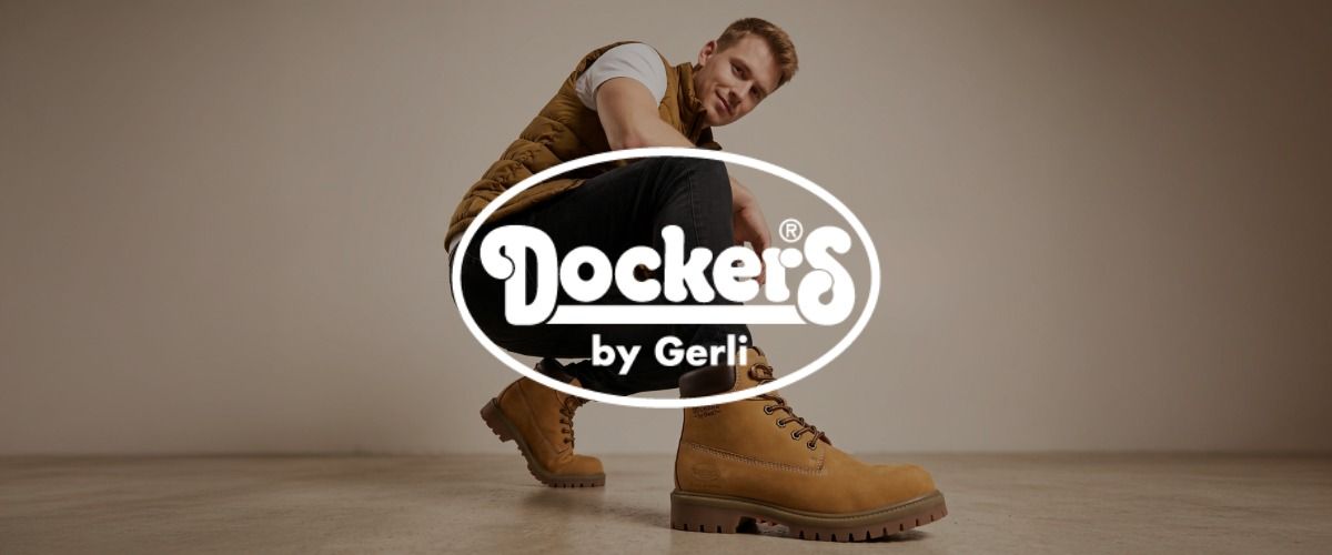 Ein Mann sitzt in der Hocke, er trägt hellbraune Stiefel und Freizeitkleidung. Das Logo der Marke Dockers überlagert das Bild.