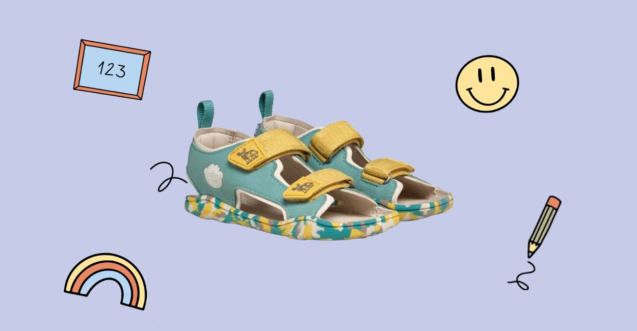 Türkisfarbene Kindersandalen mit gelben Riemen auf blauem Hintergrund, umgeben von verspielten Motiven: Smiley, Bleistift, Regenbogen und Tafel.