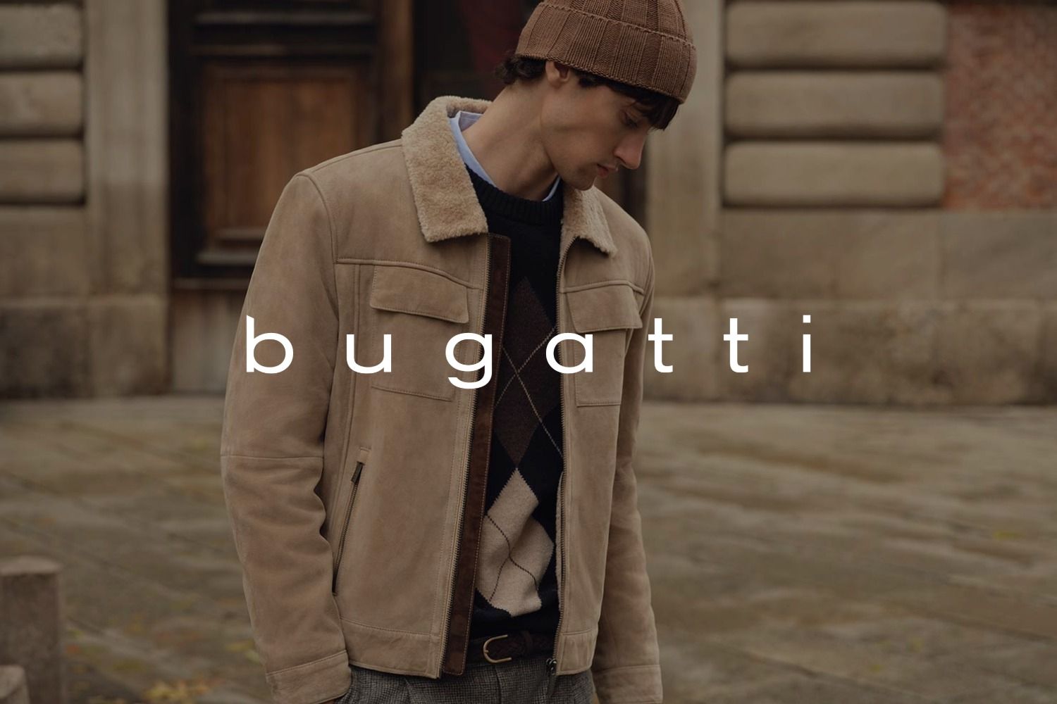 Eine Person in einer beigen Jacke und einer Strickmütze steht im Freien. Das Logo der Marke bugatti überlagert das Bild.