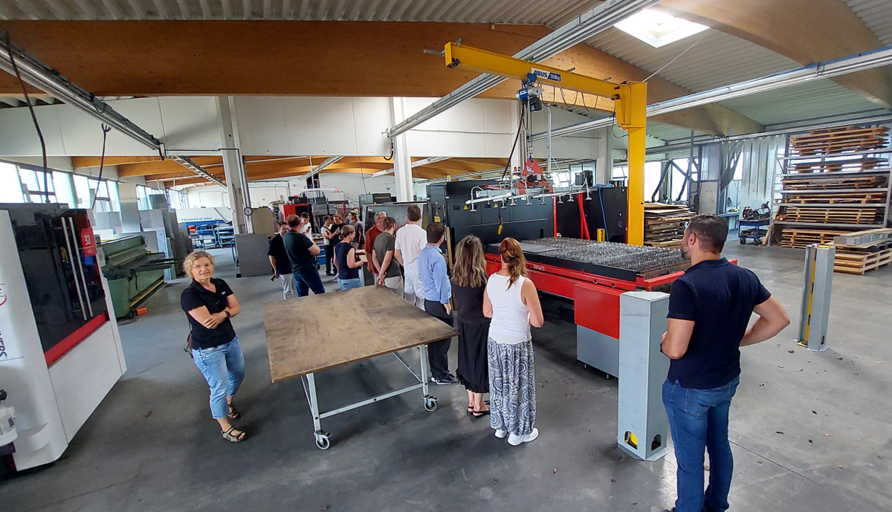 Several people are standing in the workshop, looking at the machines.