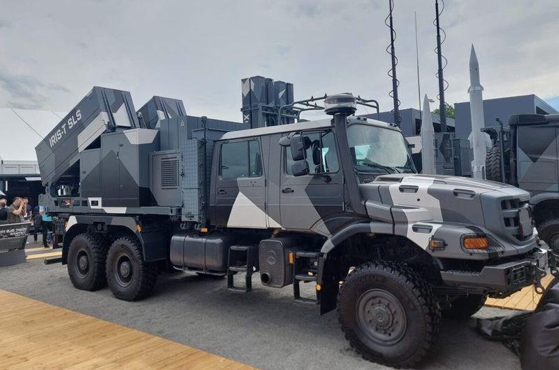 An IRIS-T-SLS MK4 military vehicle on display at the trade fair against a cloudy sky.