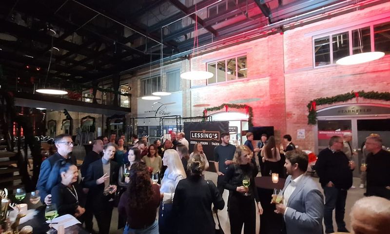 Many people stand in the entrance area of the restaurant and drink together.