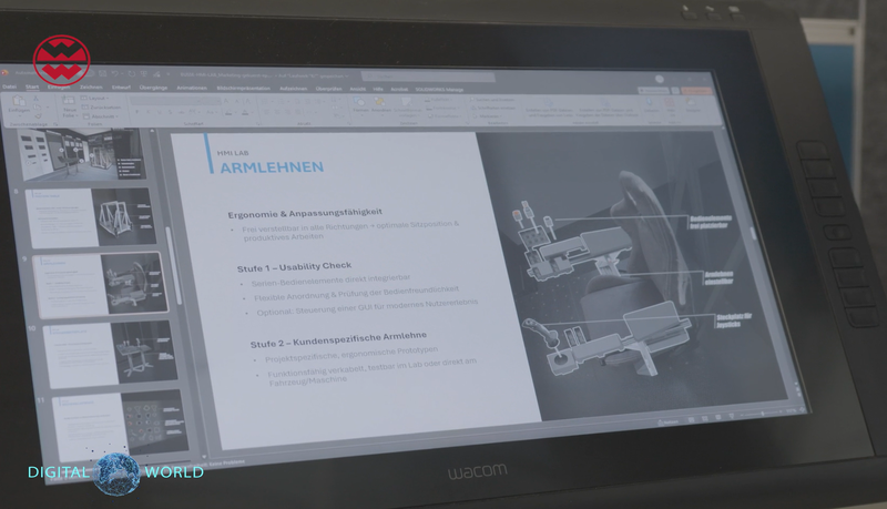 Presentation slide on a tablet showing ergonomic armrest design, with text in German and illustration of a seat with labeled components.