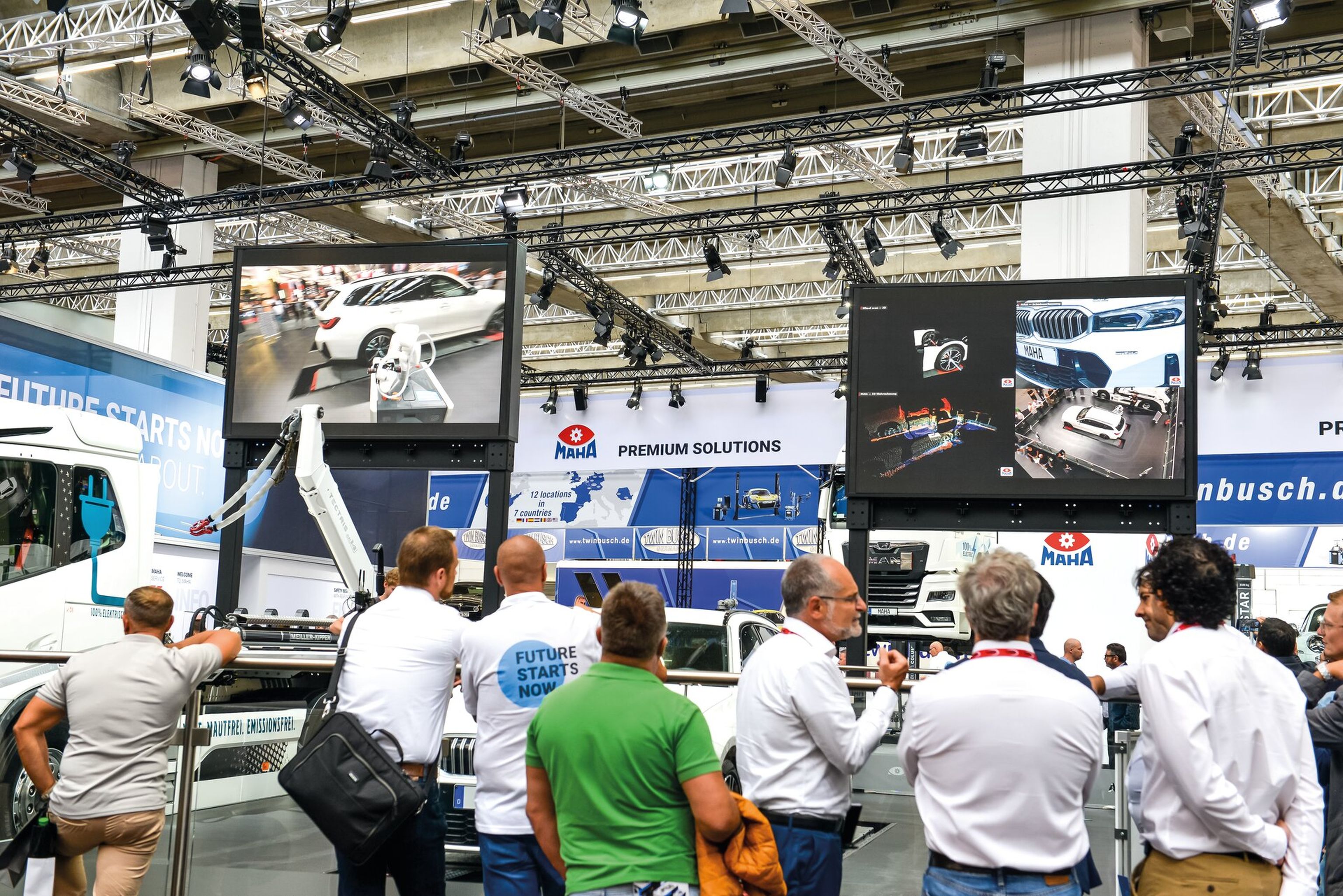 Viele Personen sind versammelt und schauen sich den Messestand von MAHA an.