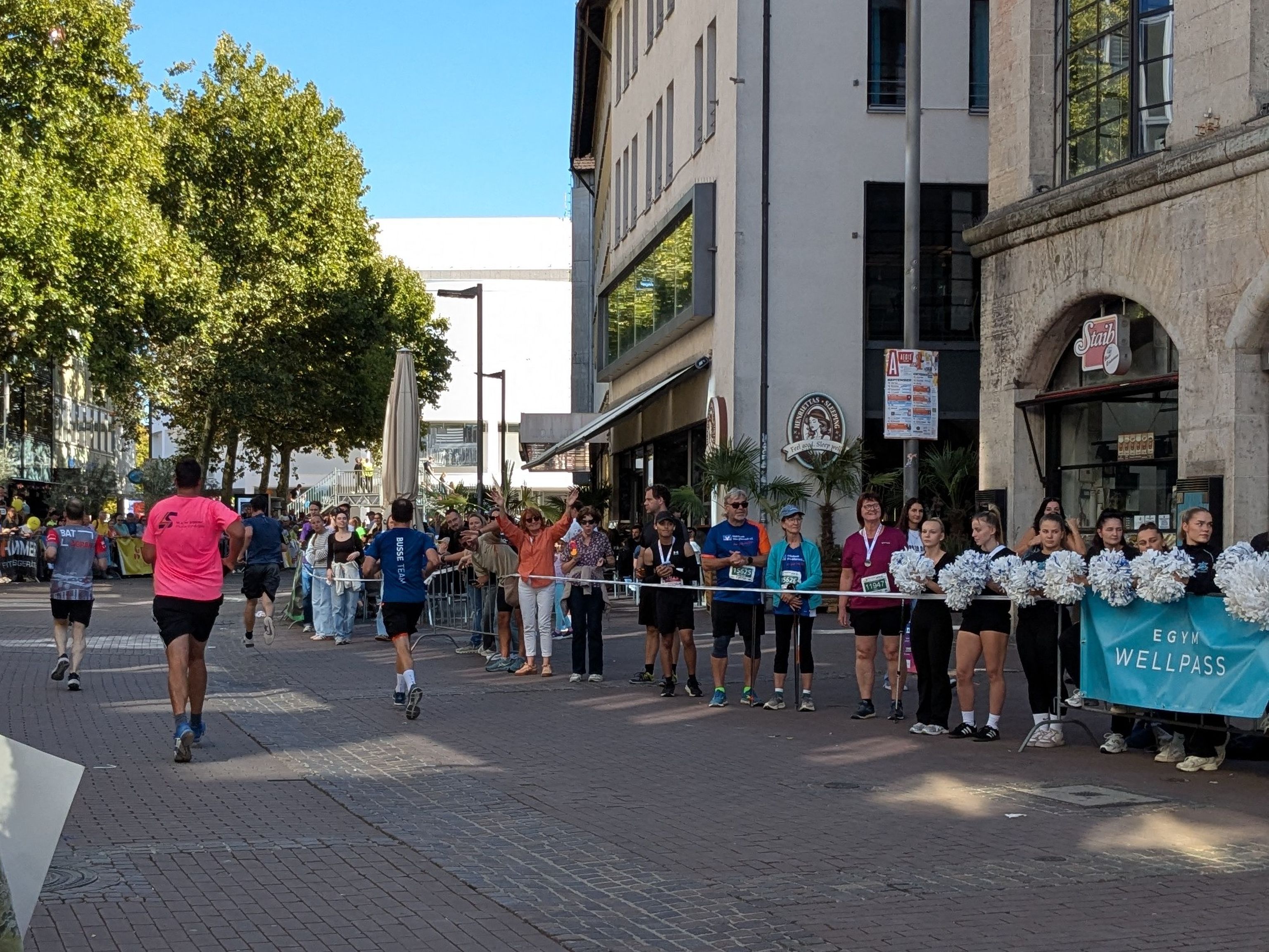 The participants are jogging and the spectators on the sidelines are cheering them on.
