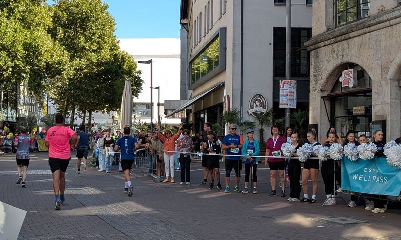 The participants are jogging and the spectators on the sidelines are cheering them on.