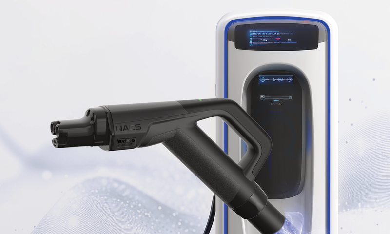 Der NACS-Stecker vor einer Ladesäule.