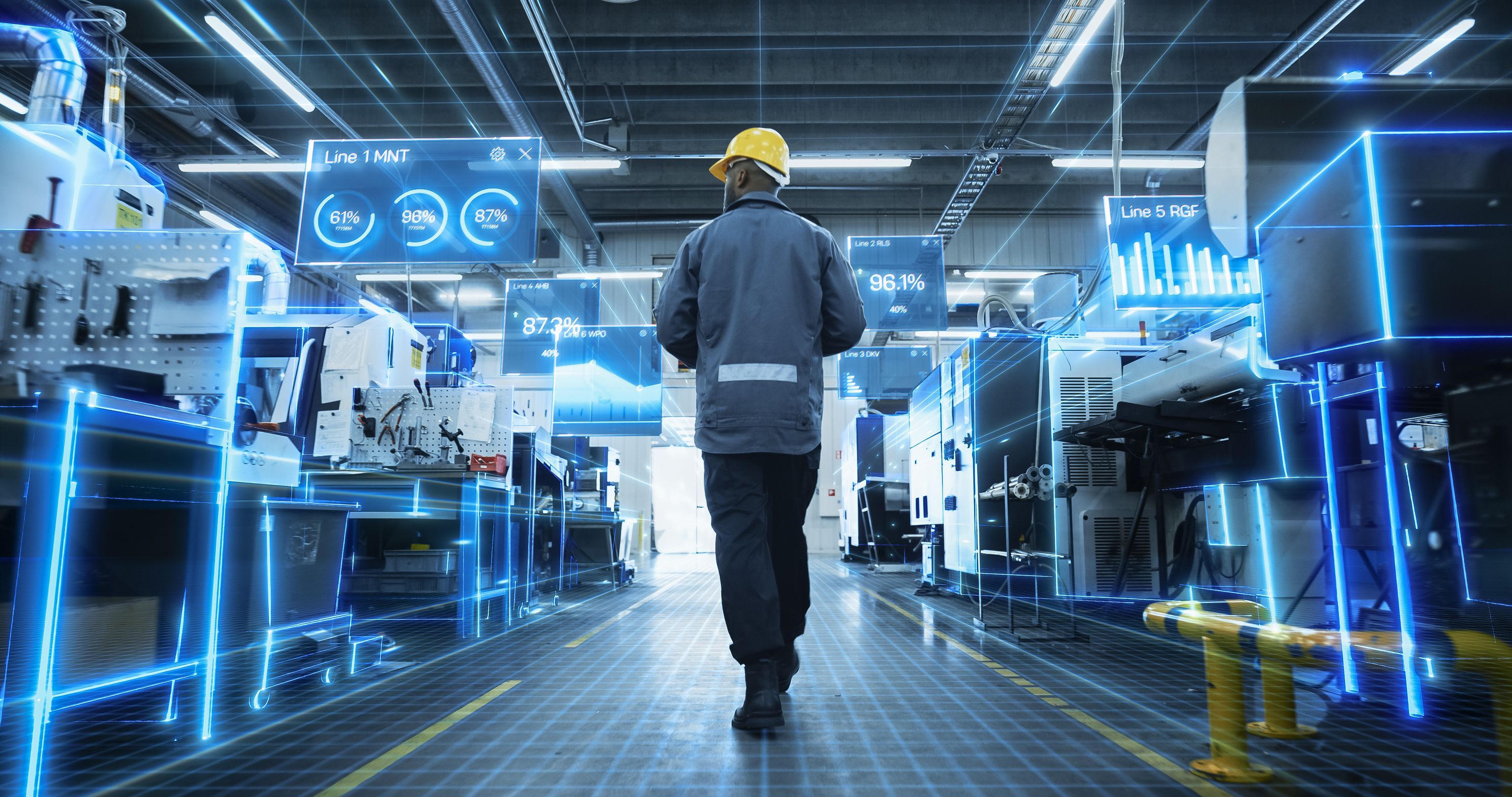 A worker in a hard hat walks through a high-tech factory with holographic data displays highlighting production line metrics.