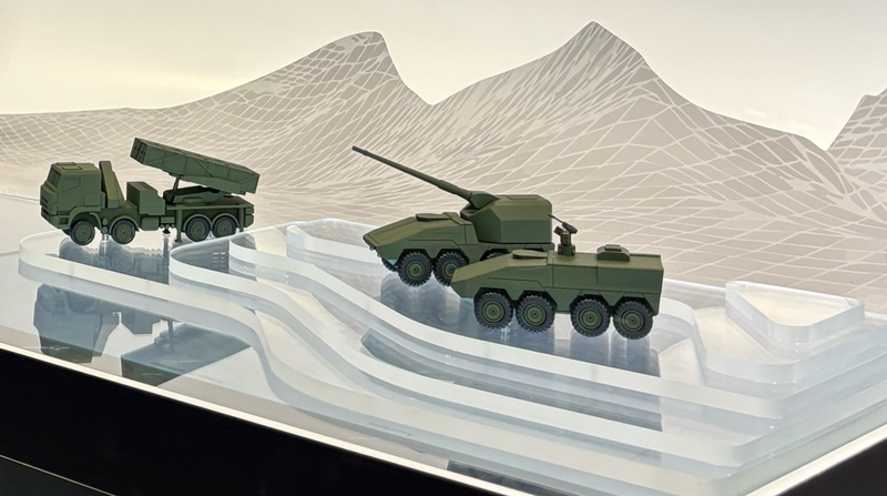Miniatur Militärfahrzeuge stehen auf einer abstrakten Landschaft aus Glas.