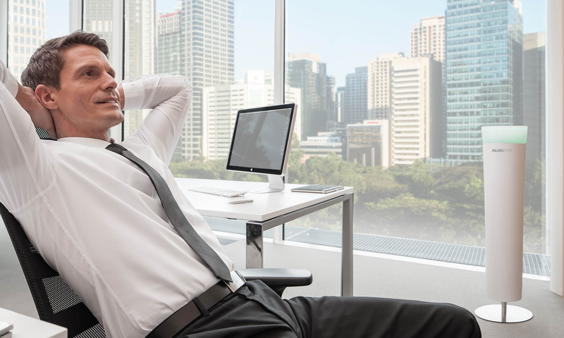 Mann sitzt entspannt im Büro neben seinem Raumluftfilter