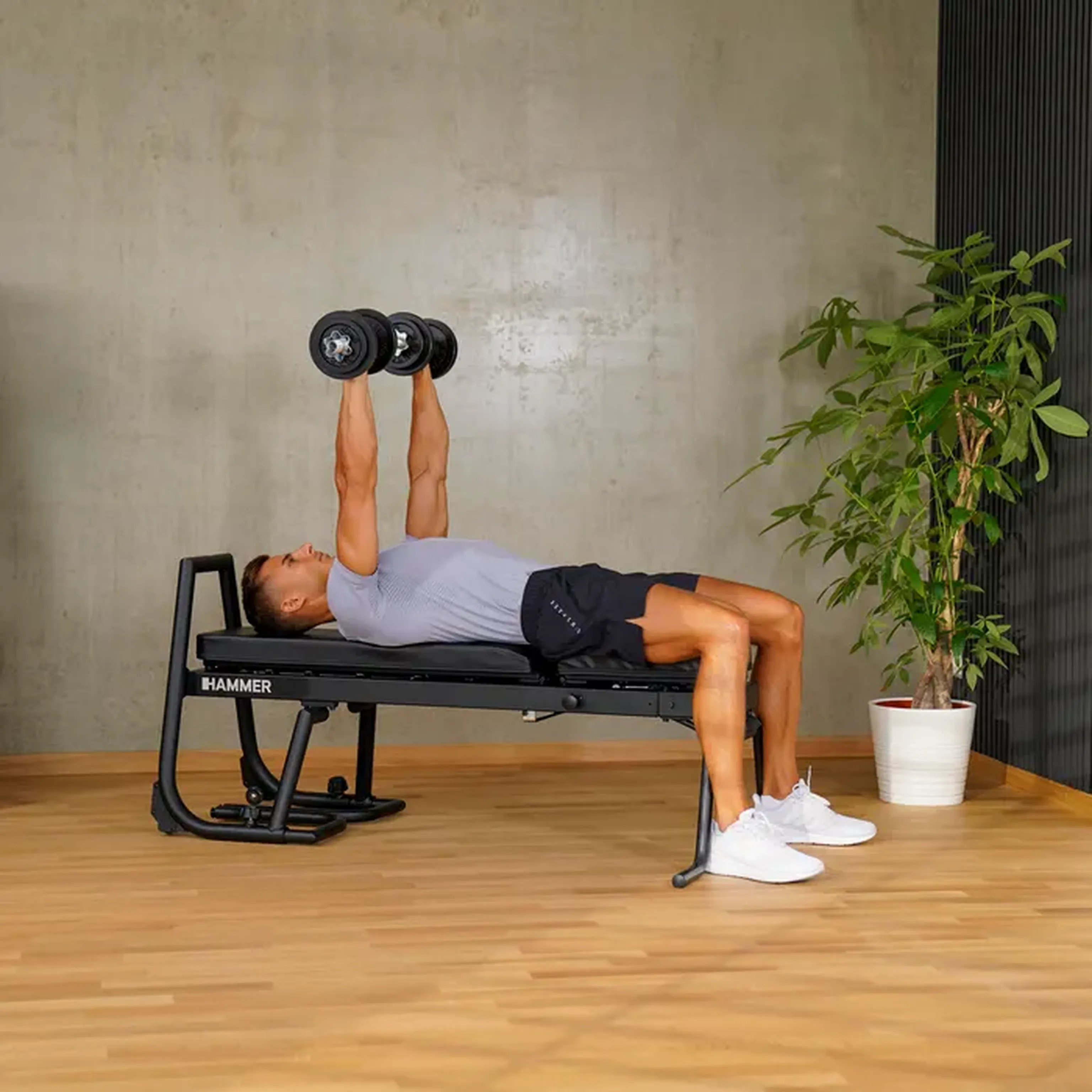 Person macht ein einem Fitness Gerät Übungen mit Hanteln.