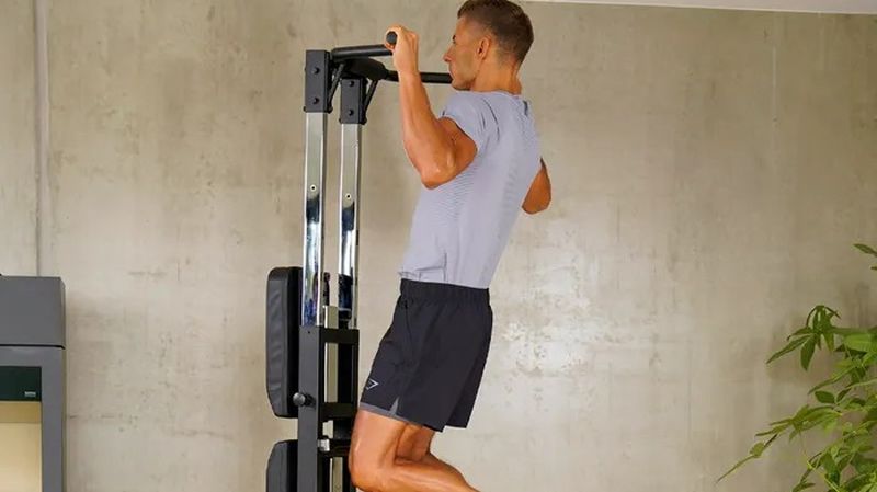 Person macht ein einem Fitness Gerät einen Klimmzug.