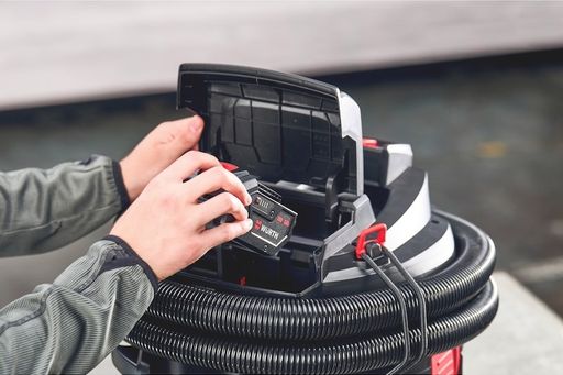Person setzt einen Akku in eine Maschine ein.