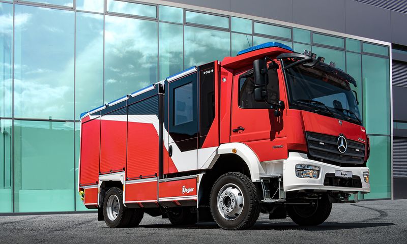 Feuerwehrfahrzeug vor Gebäude von links vorne