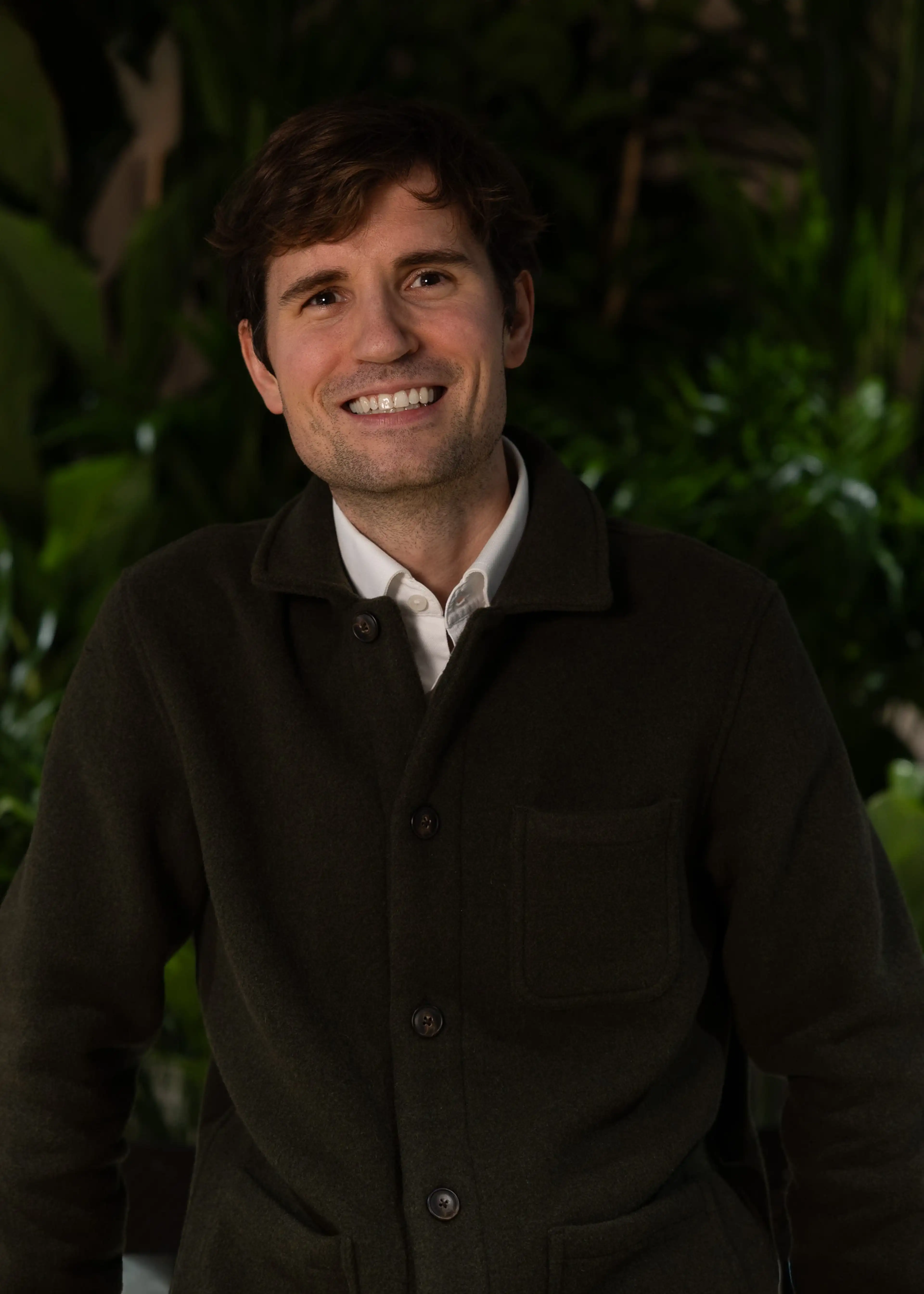 Smiling man with brown hair in green jacket