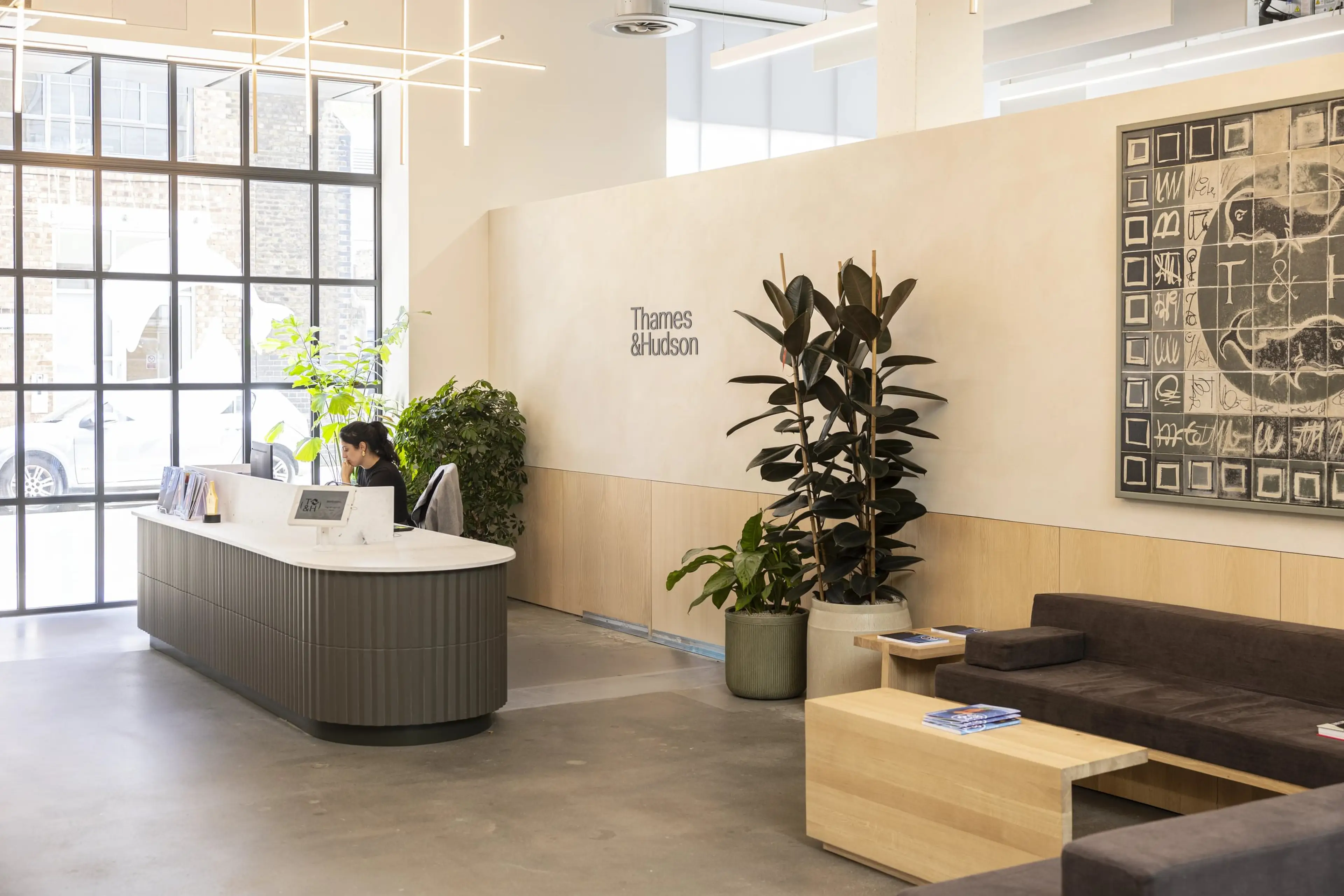 A brightly lit office reception, populated by floor standing office plants.