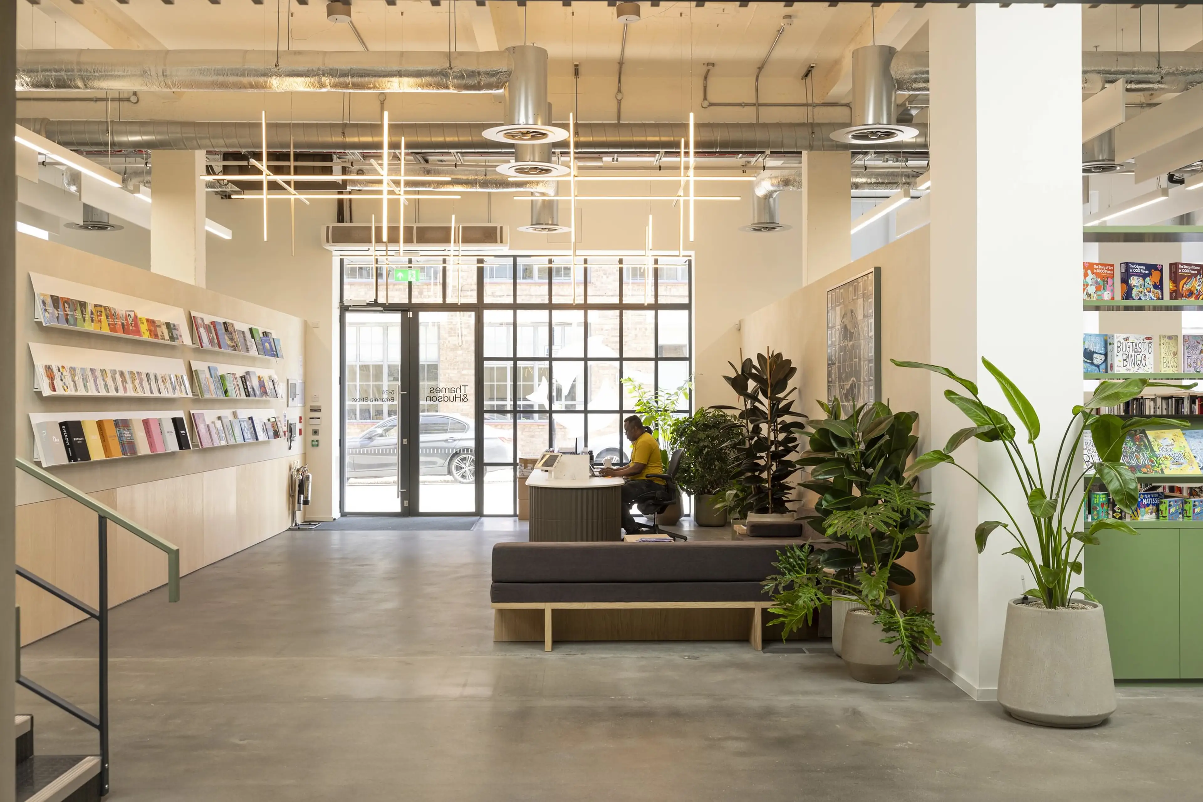 A bright glass entranceway to an office. The desk is surrounded by floor standing plants.