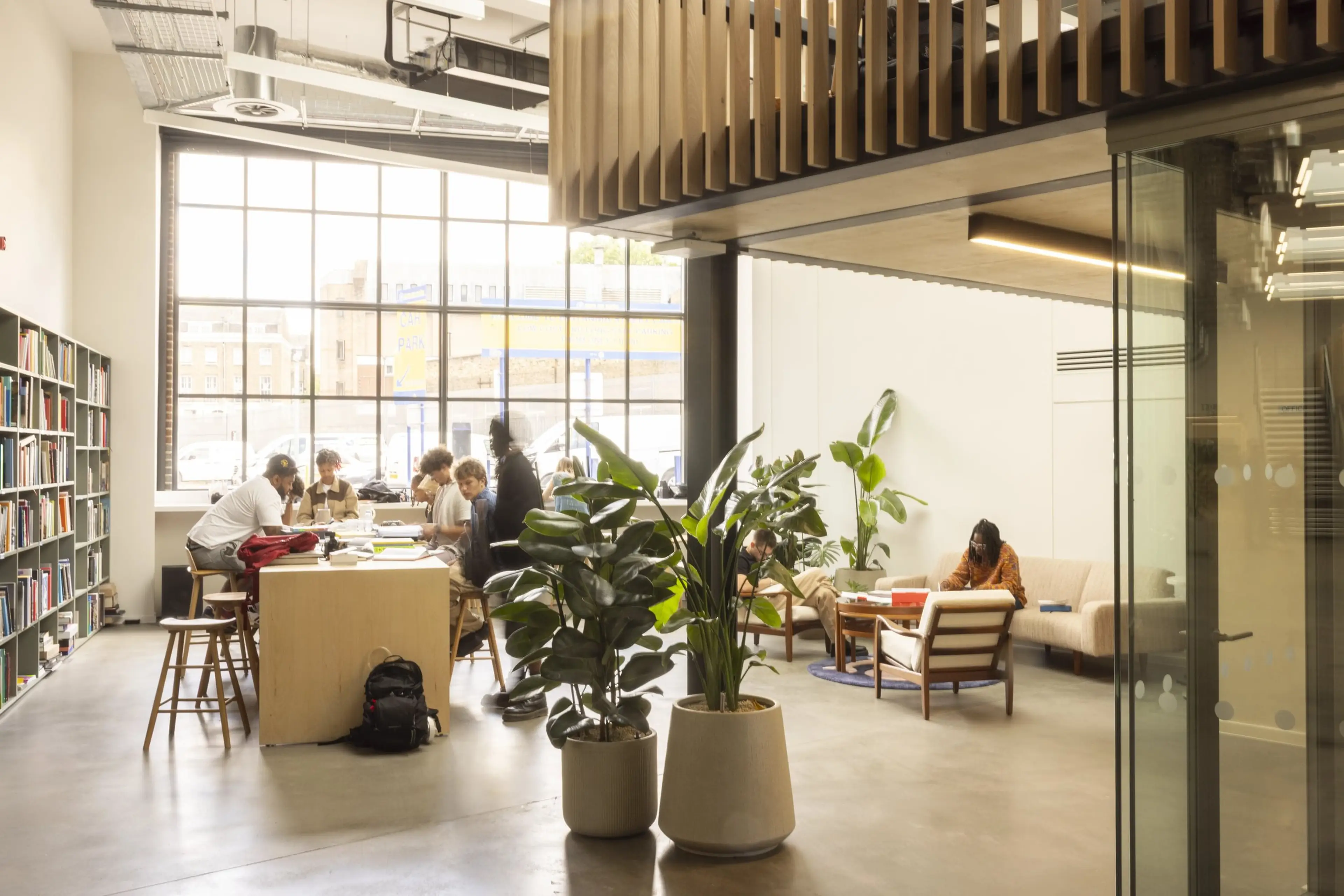 A well lit communal office space full of people, with office plants in the centre.