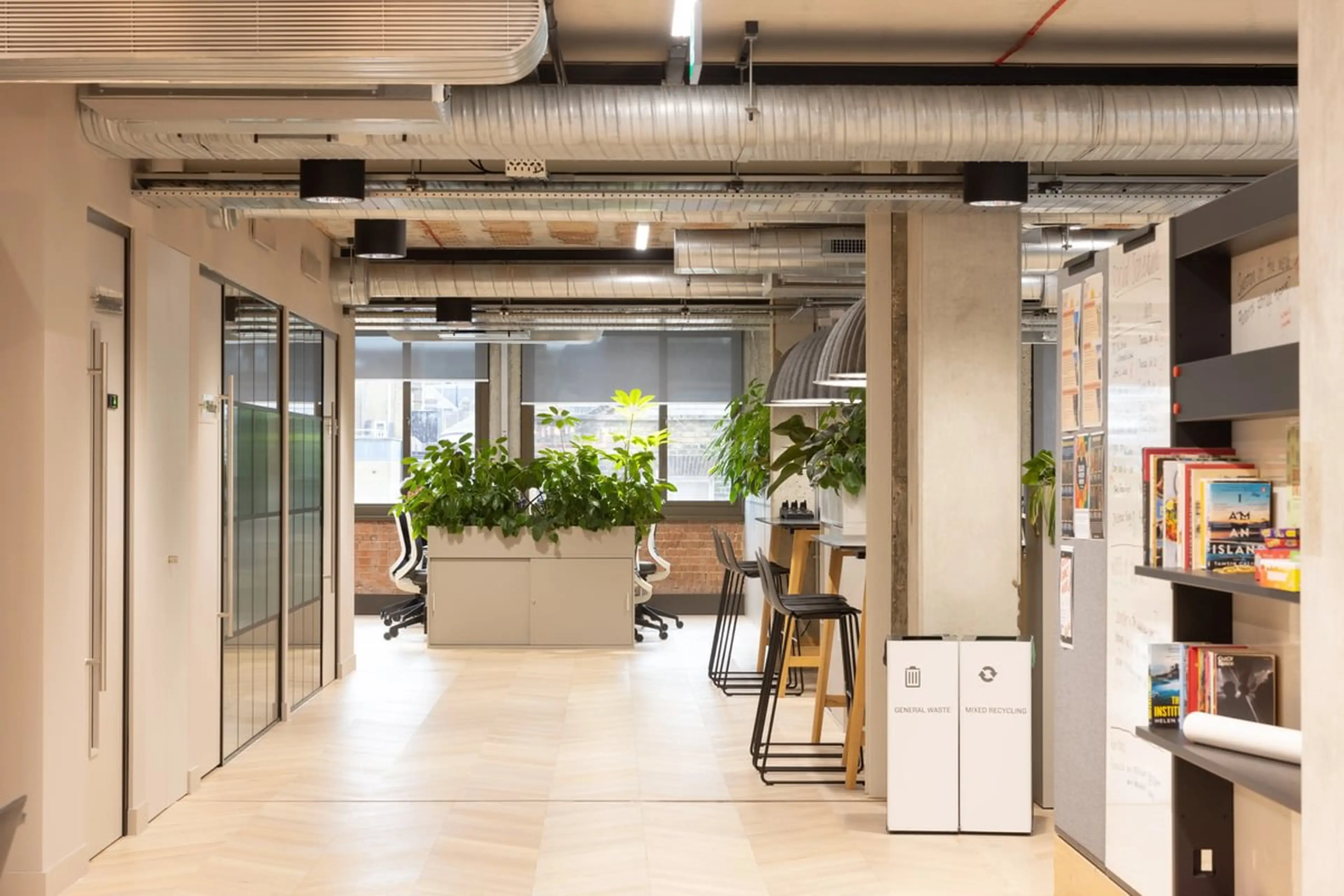 A long hallway in an office, with tall, structural planting at the desktop at the back