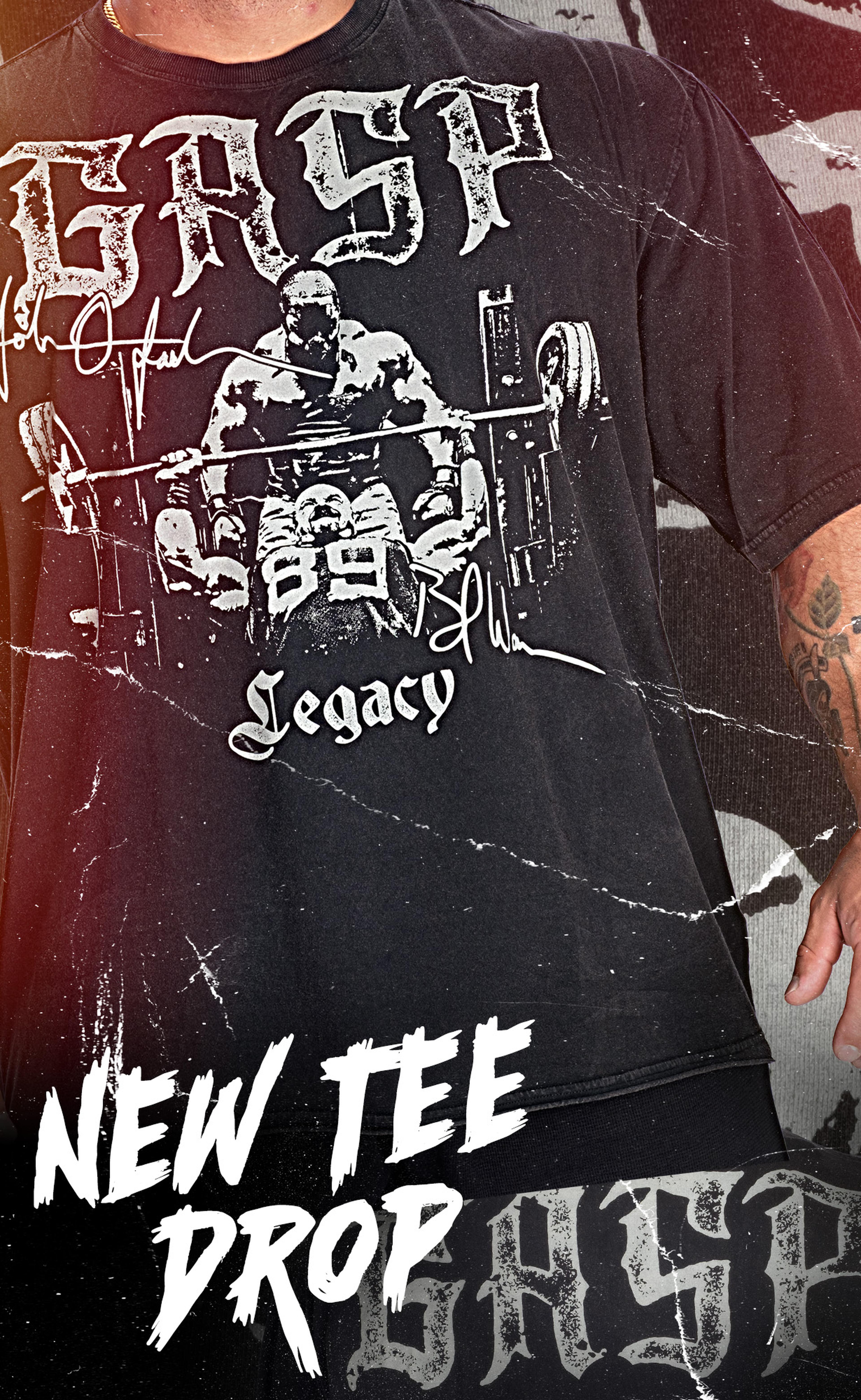Man wearing a black T-shirt with a graphic of a bodybuilder bench pressing, featuring the text "GASP Legacy." Text overlay reads "New Tee Drop."
