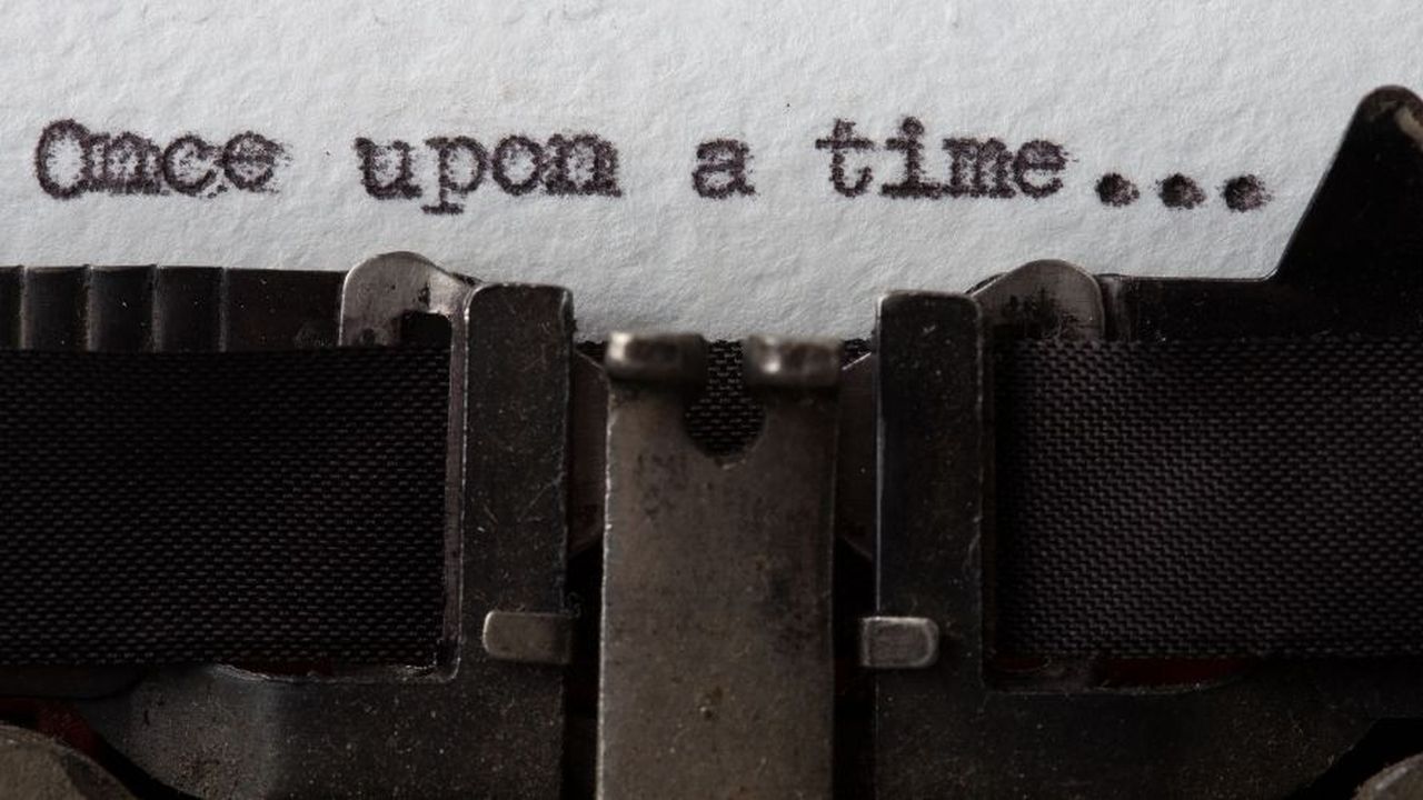 Close-up of a typewriter typing "Once upon a time..." on white paper, with visible typebars and ribbon.
