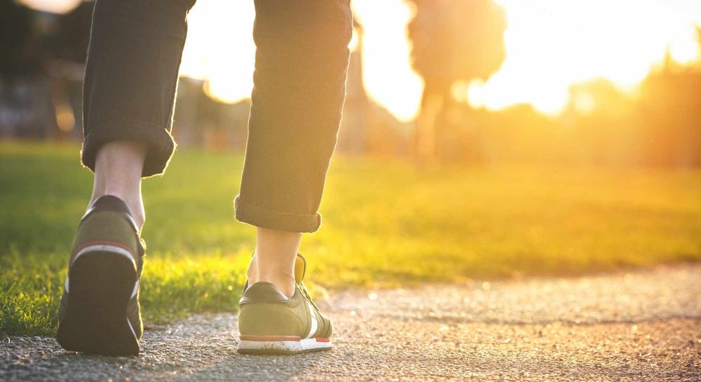 Woman walking in the park. Close-up of shoe. Sunset.