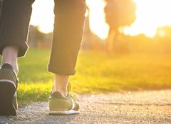 Woman walking in the park. Close-up of shoe. Sunset.