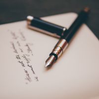 Pen resting on paper with a short written message.
