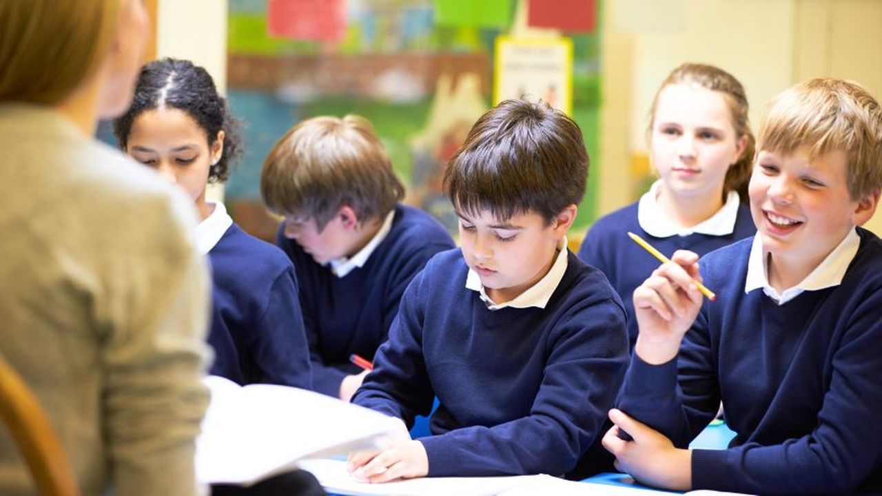 Primary school children in a classroom with a teacher presenting.