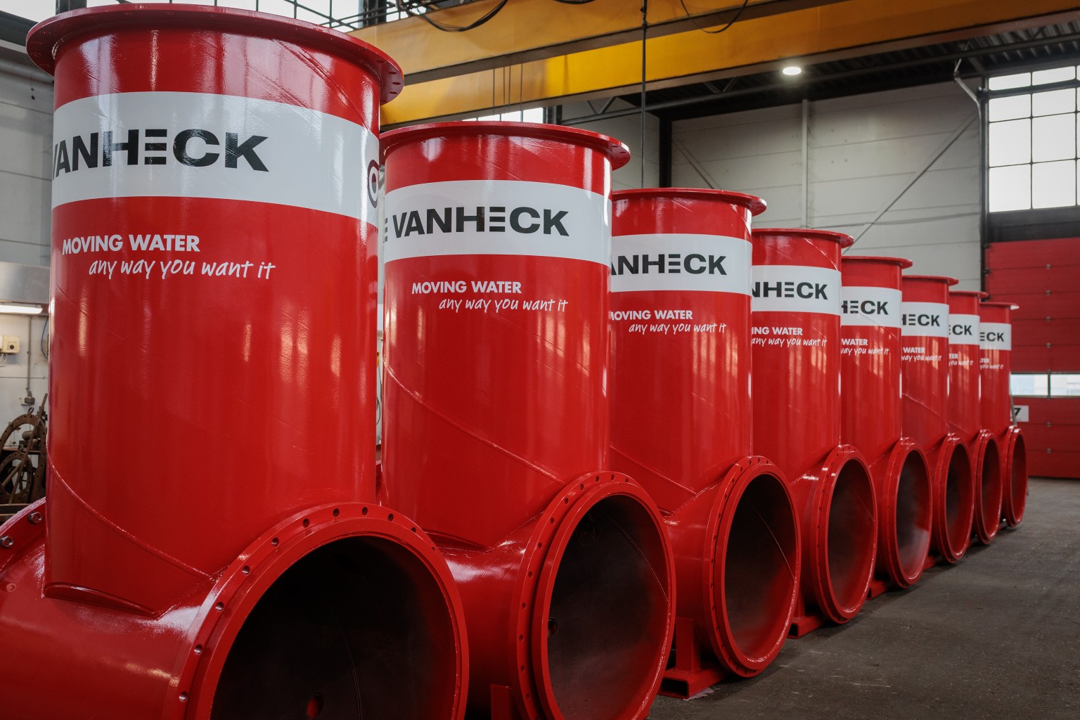 Hevelketels Een rij van rode constructies van stalen leidingwerk met de tekst "Van Heck Moving water any way you want it"