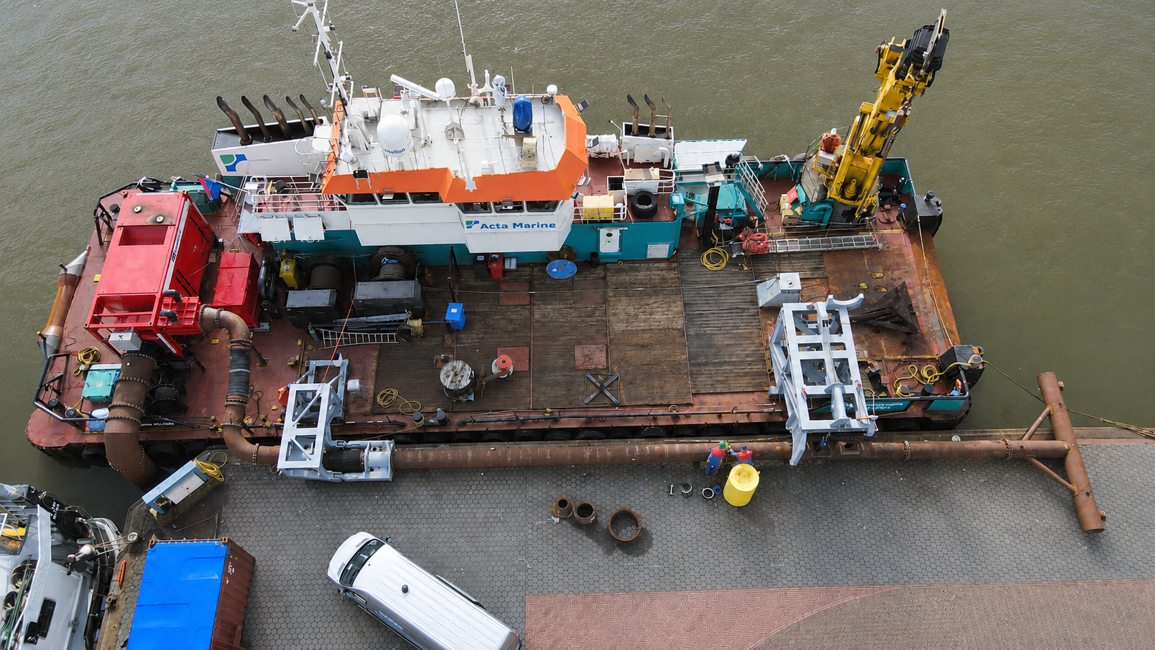 Een multicat schip aan de kade met daarop een gele kraan en een rode pomp die is aangesloten op een WID tool