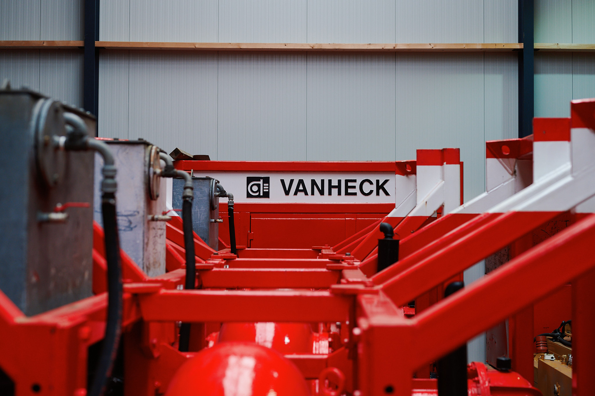 Rij van Hk500's Een rij van pompsets naast elkaar in een loods, uitkijkend op een container met daarop het opschrift: "Van Heck"