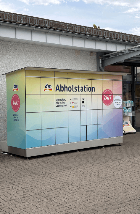 Die 24/7-Abholstation steht draußen vor einem dm-Markt.