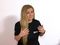 Woman in EURO PART shirt gesturing, plain background, testimonial or interview setting.