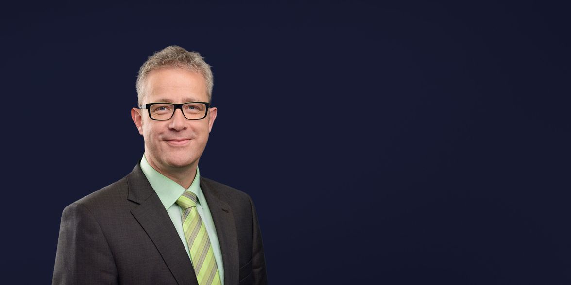 Professional man in suit and glasses on plain background, testimonial, no visible text or UI.