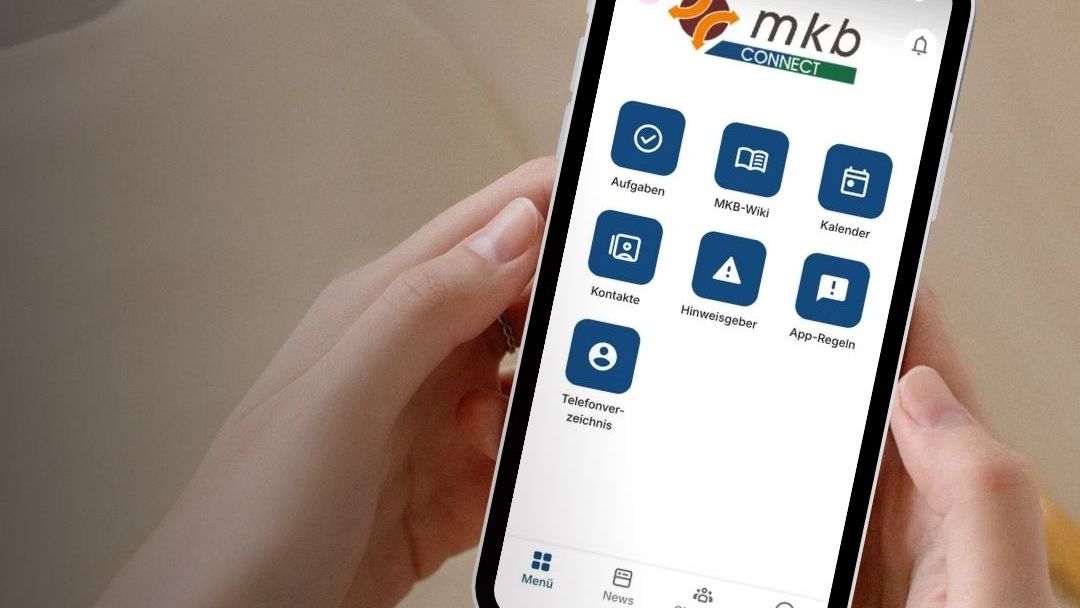Person holding phone with MKB Connect app interface in German.