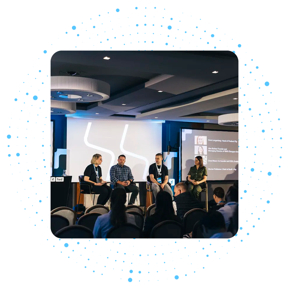 Panel discussion at a conference with four speakers on stage.