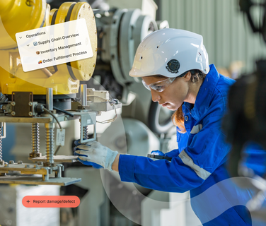 Worker in blue coveralls and white helmet operates machinery in an industrial setting, focusing intently on the task.