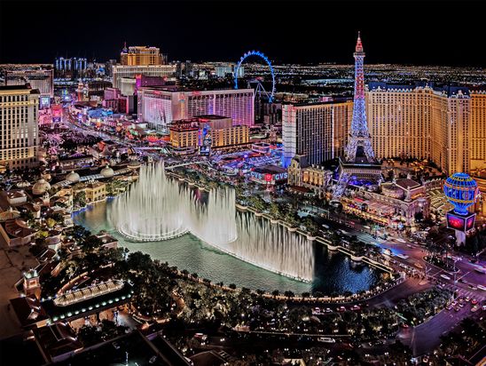 Night view of the Las Vegas Strip with Bellagio fountains and city lights.