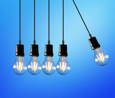 Five hanging light bulbs on blue gradient background, one bulb swinging to the right, decorative image.